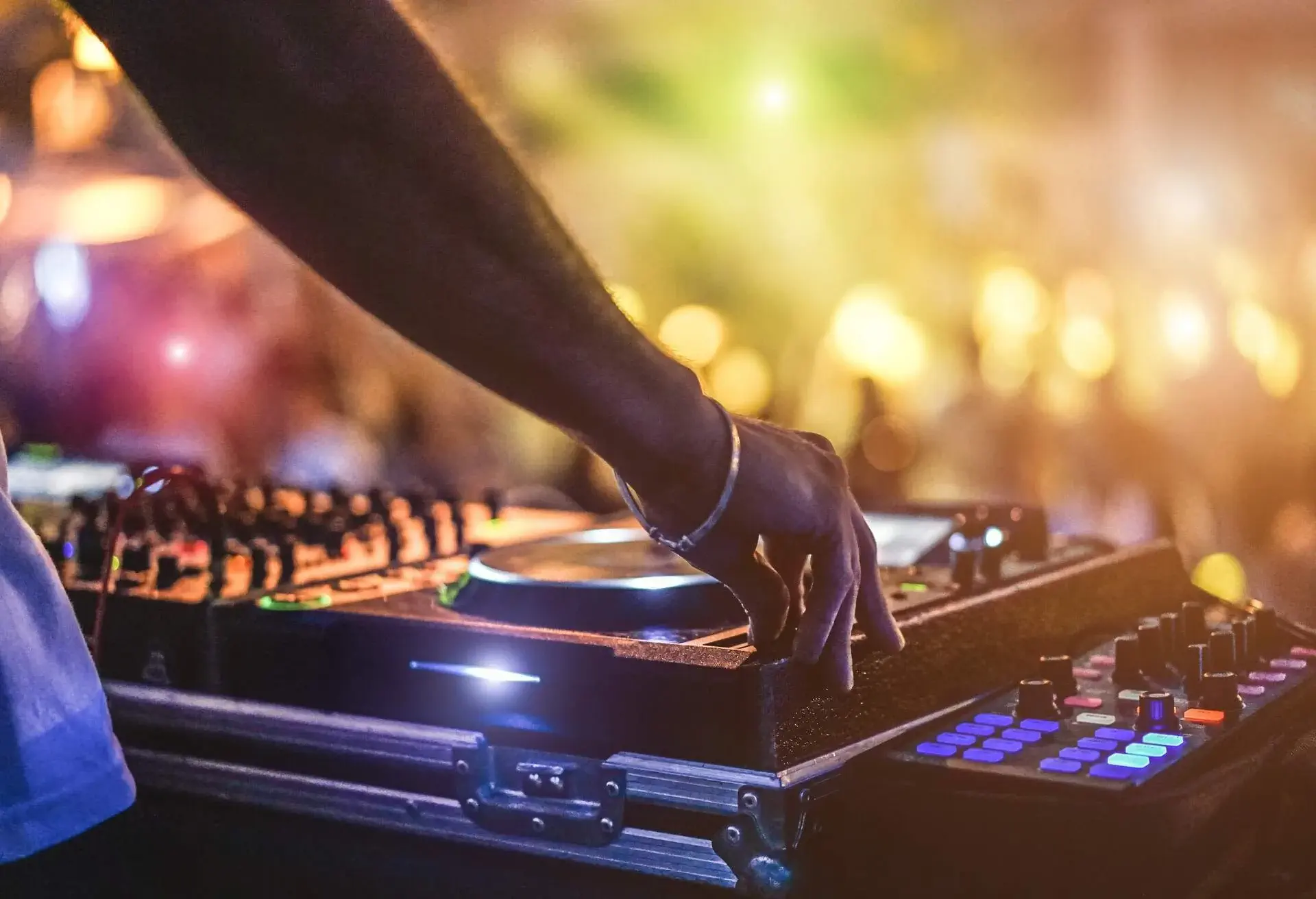 Dj mixing outdoor at beach party festival with crowd of people in background
