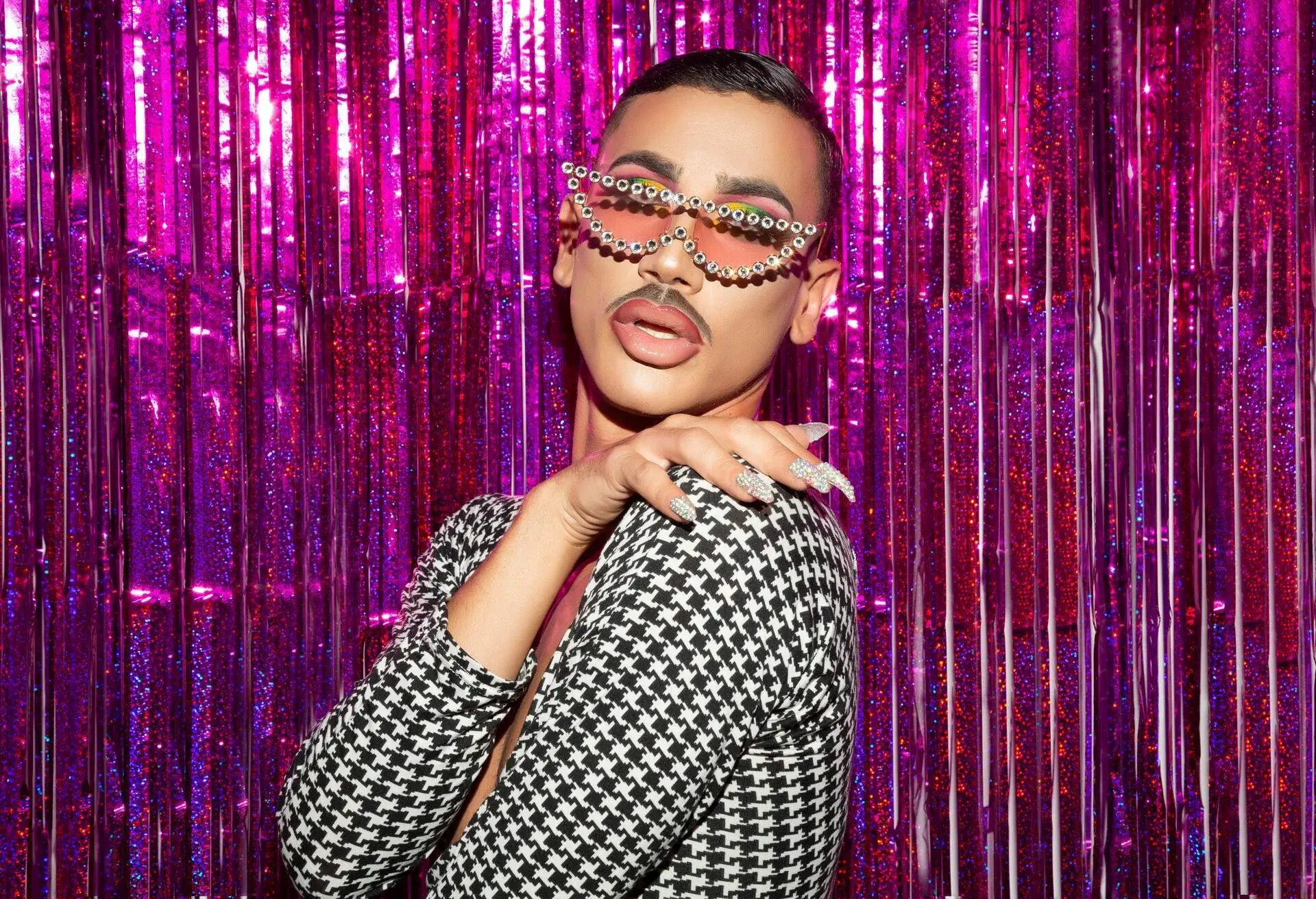 Closeup portrait of drag queen diva with fuchsia glitter background