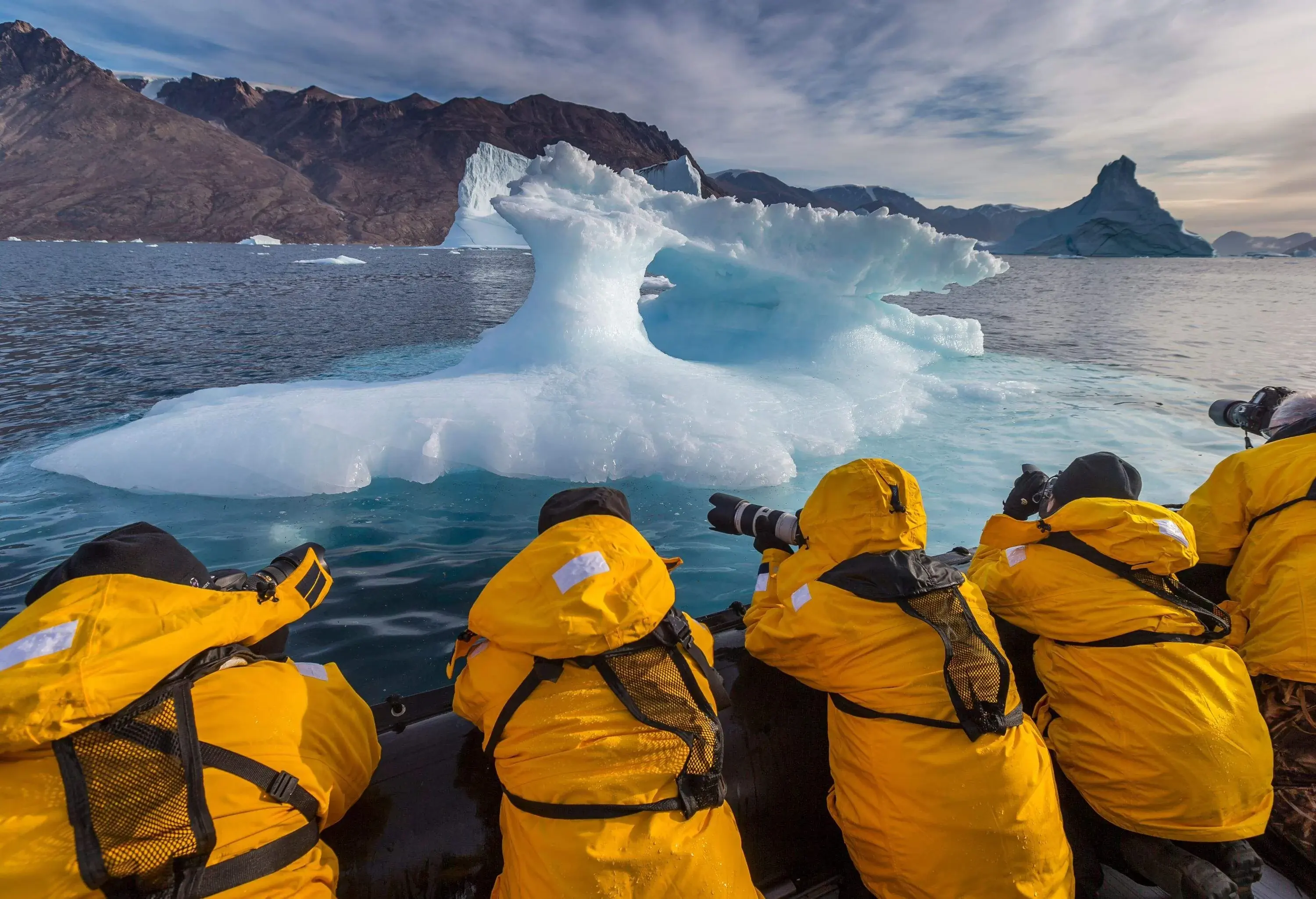 Expedition wearing yellow jackets researching and photographing icebergs in Scoresbysund, Greenland