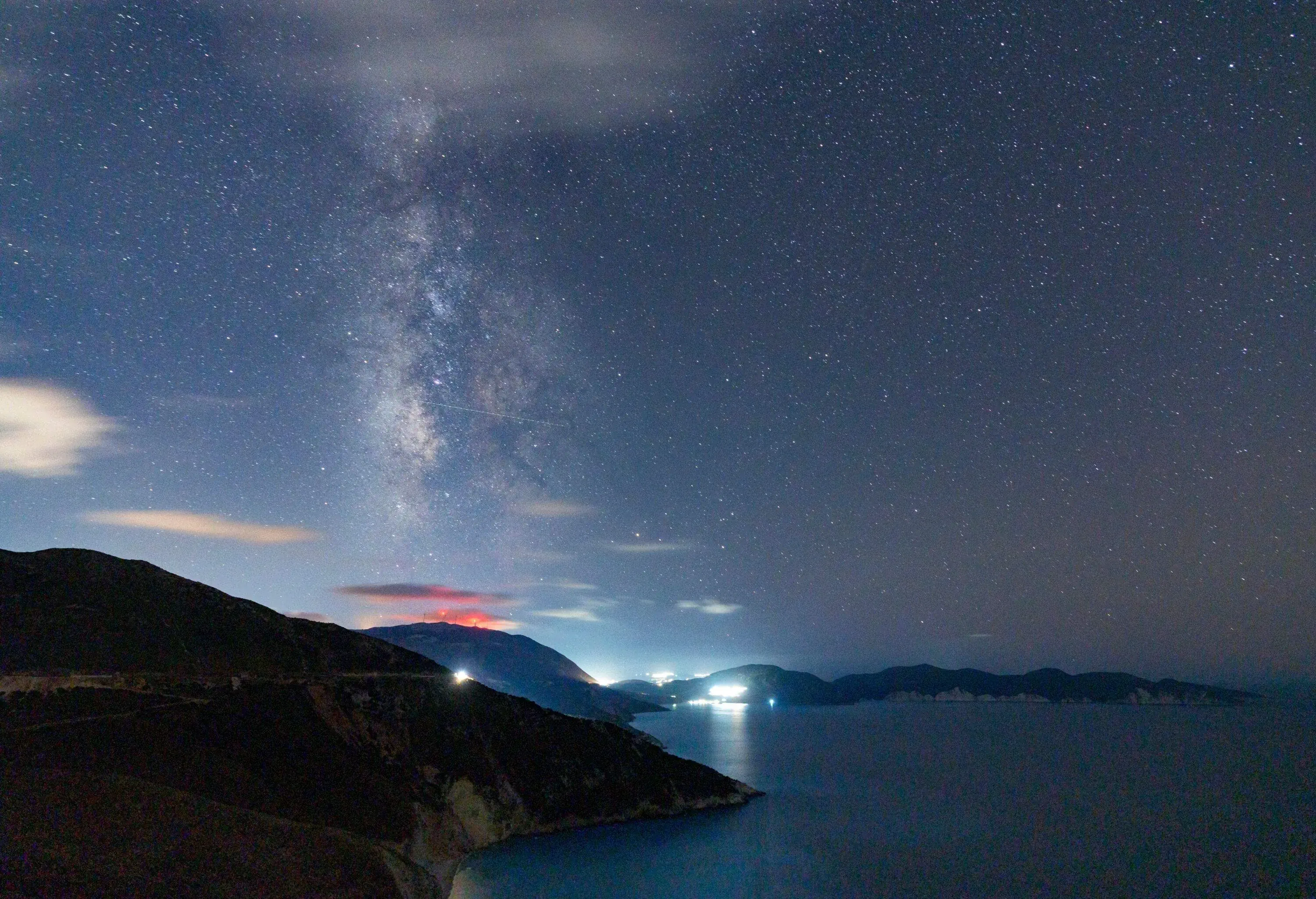 Car traveling on coastal road under Milky Way, Greece
