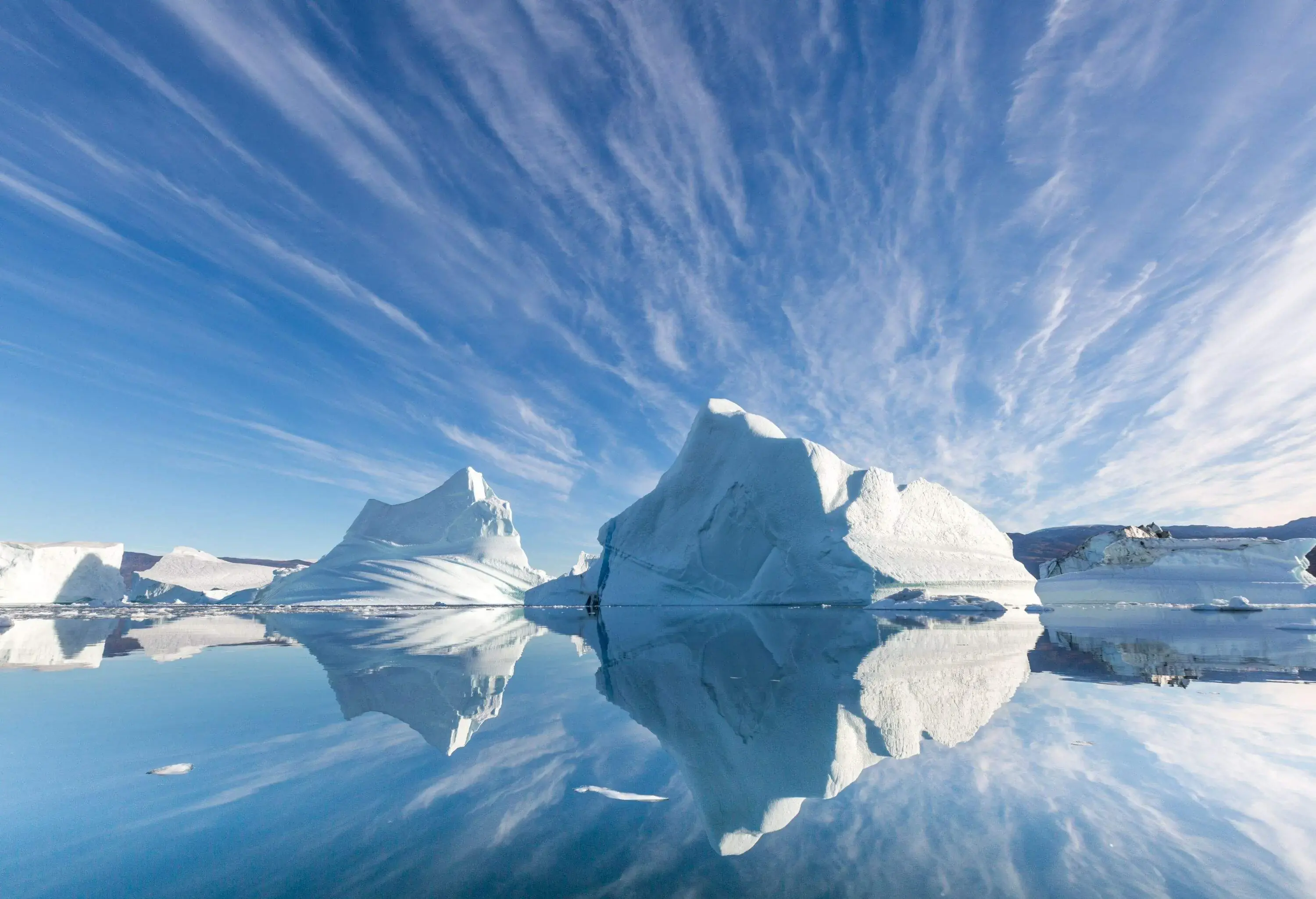 Tranquil scene of icebergs reflected in calm water with a blue sky on a calm sunny day