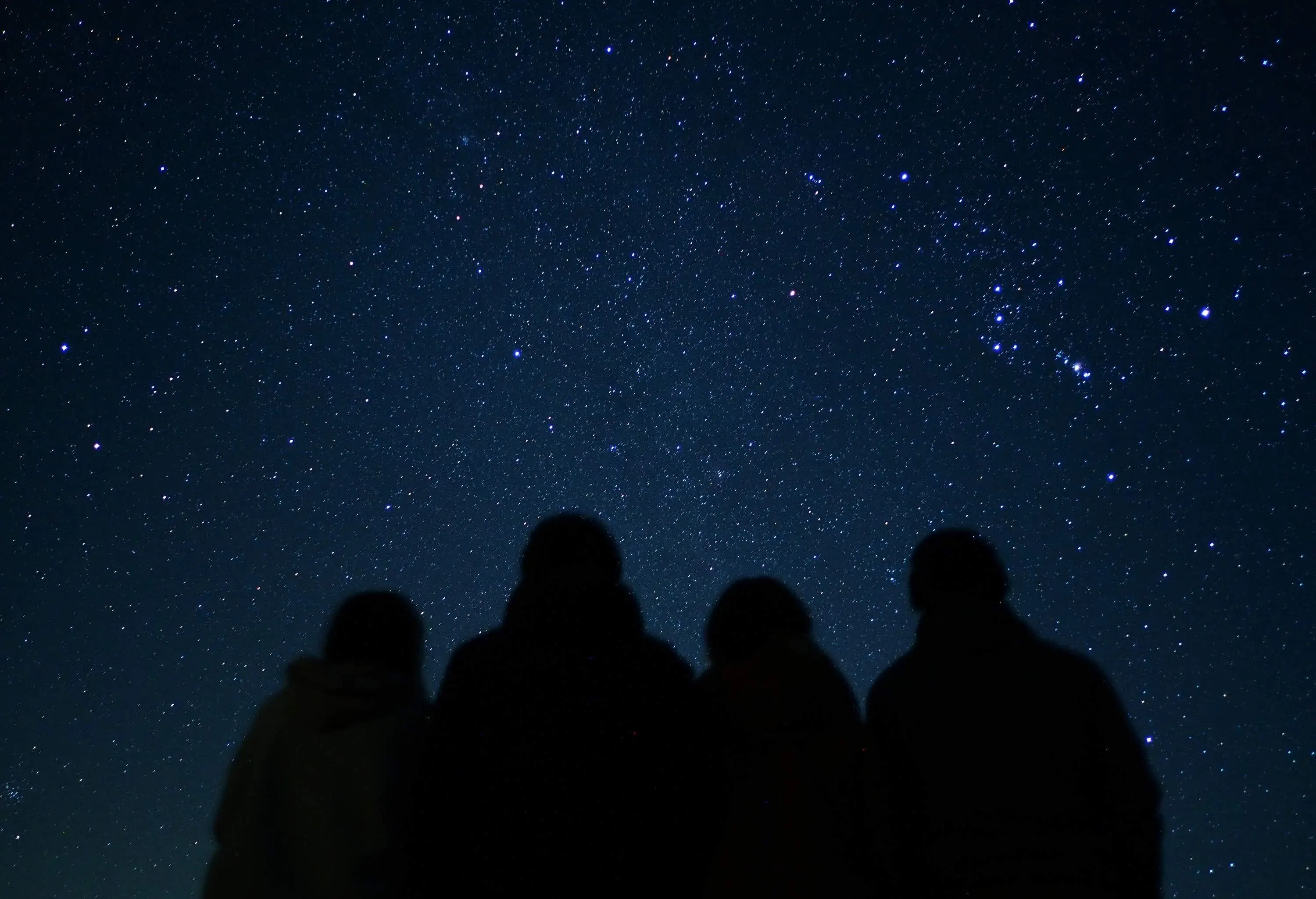 Silhouette of four people under a constellation of stars.