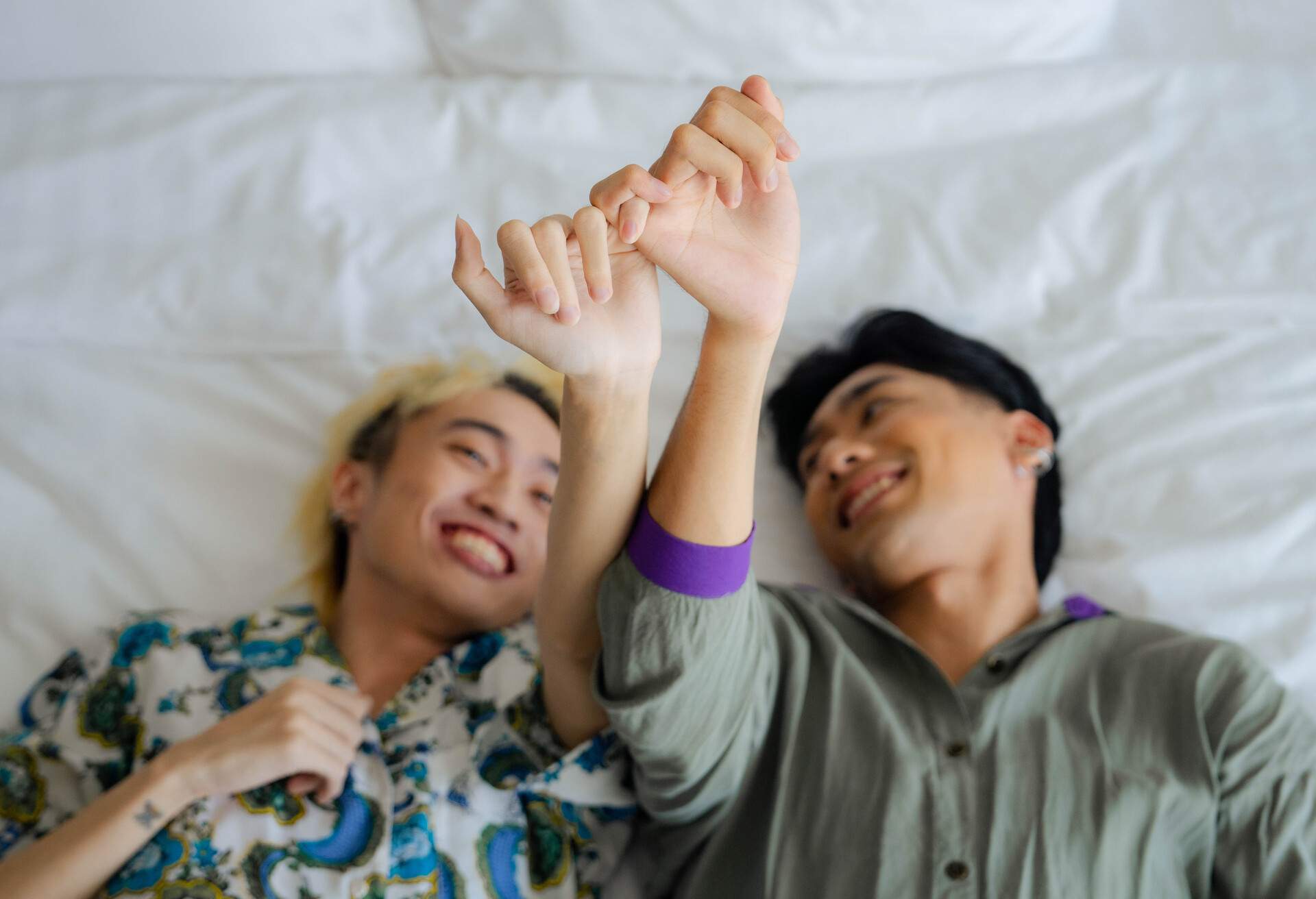 Asian Gay couples happily tease each other in bed on weekend trips. 