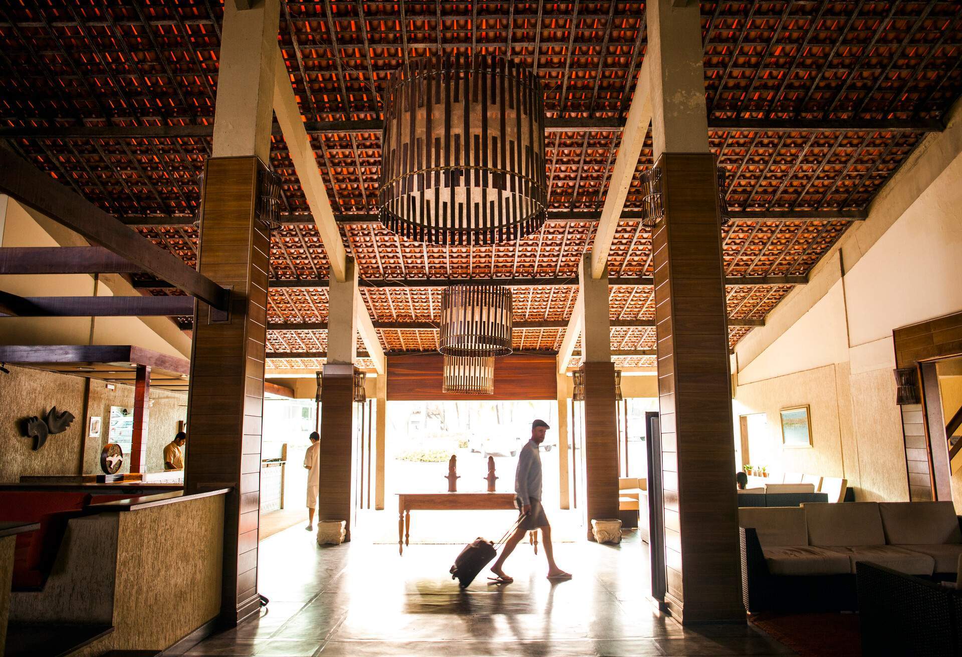 A man walking across a hotel lobby with his luggage.