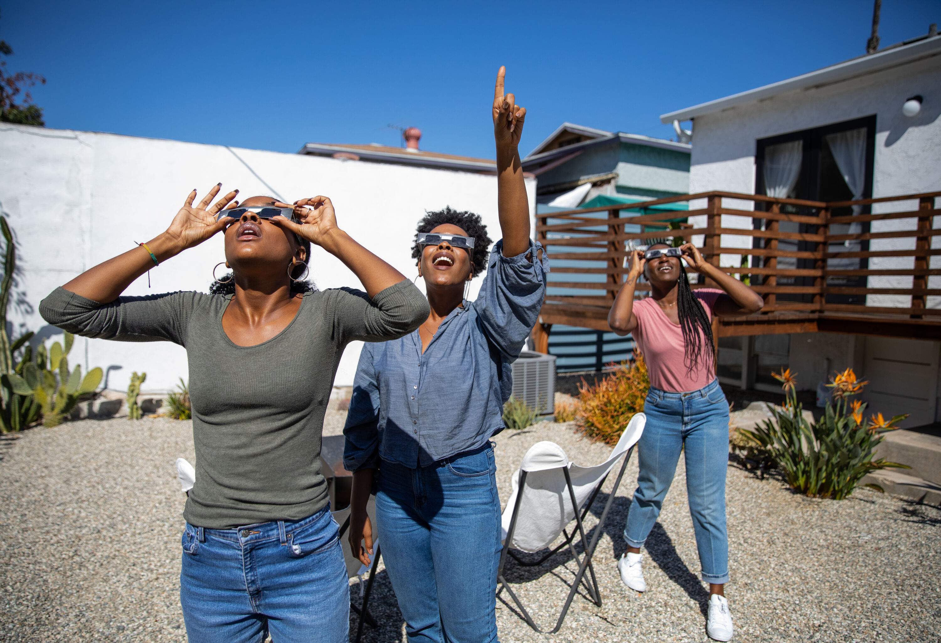 Women friends at home enjoying solar eclipse looking at the sun with eclipse sunglasses