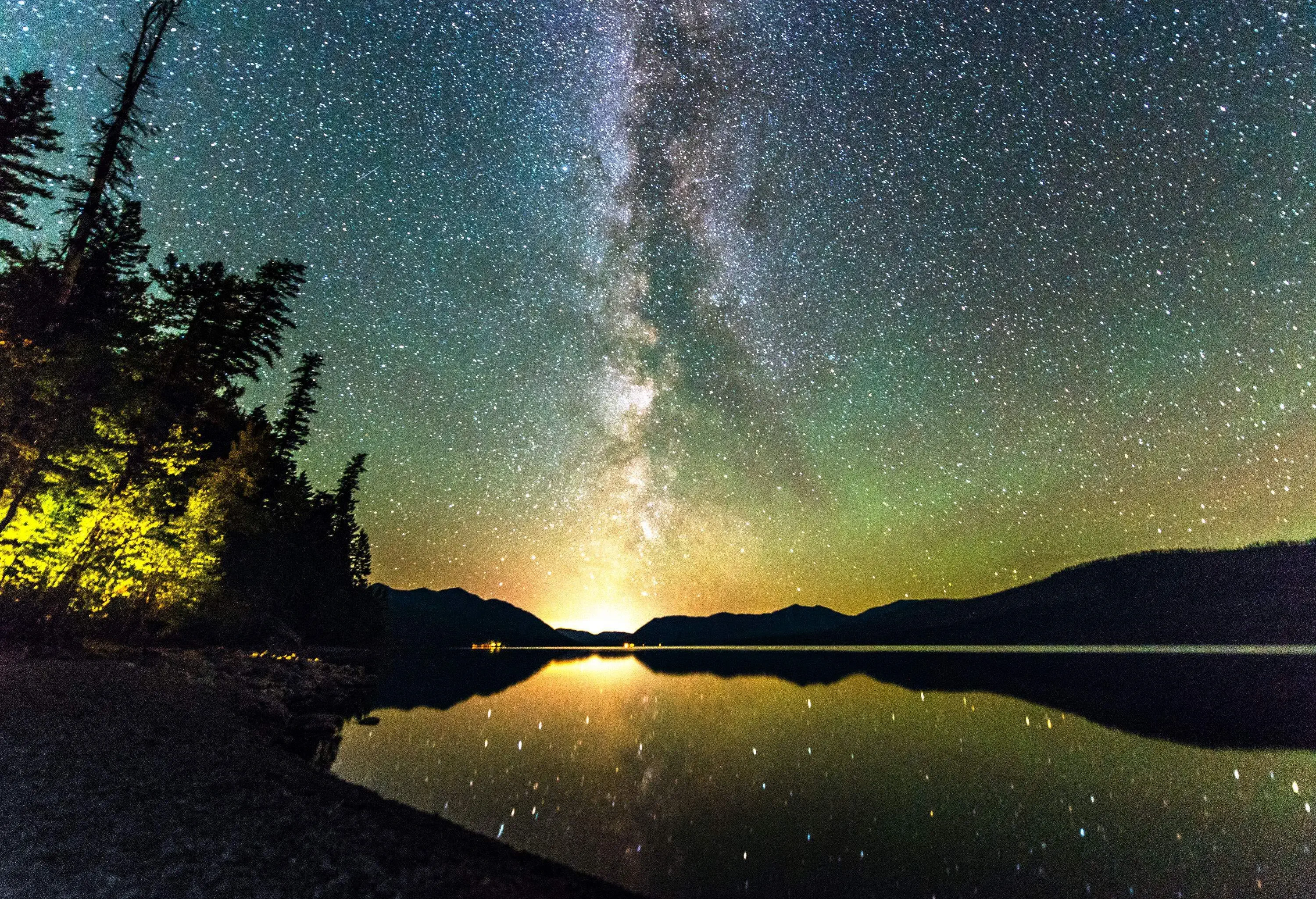 Beautiful scenery of the Northern lights and the Milky Way on the starry night sky above the lake.