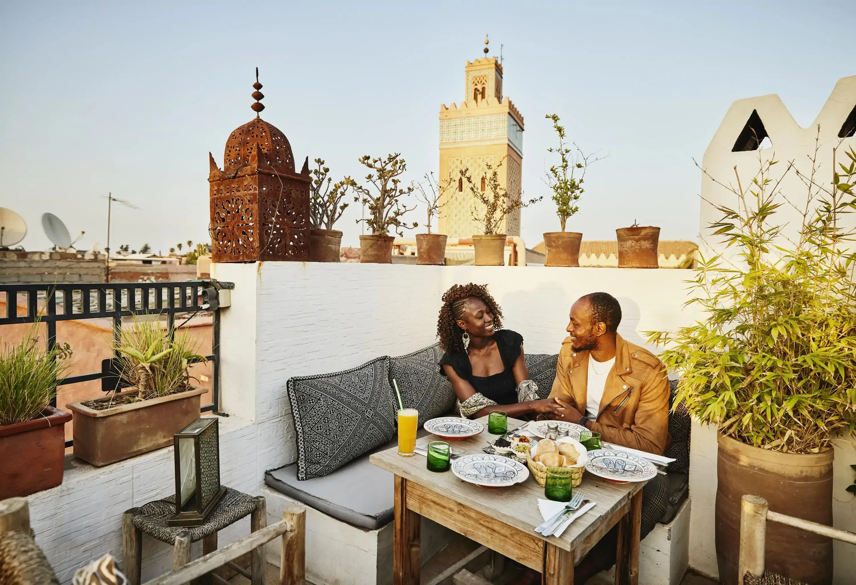 Wide shot of smiling couple dining at rooftop restaurant in the Medina of Marrakech while on vacation