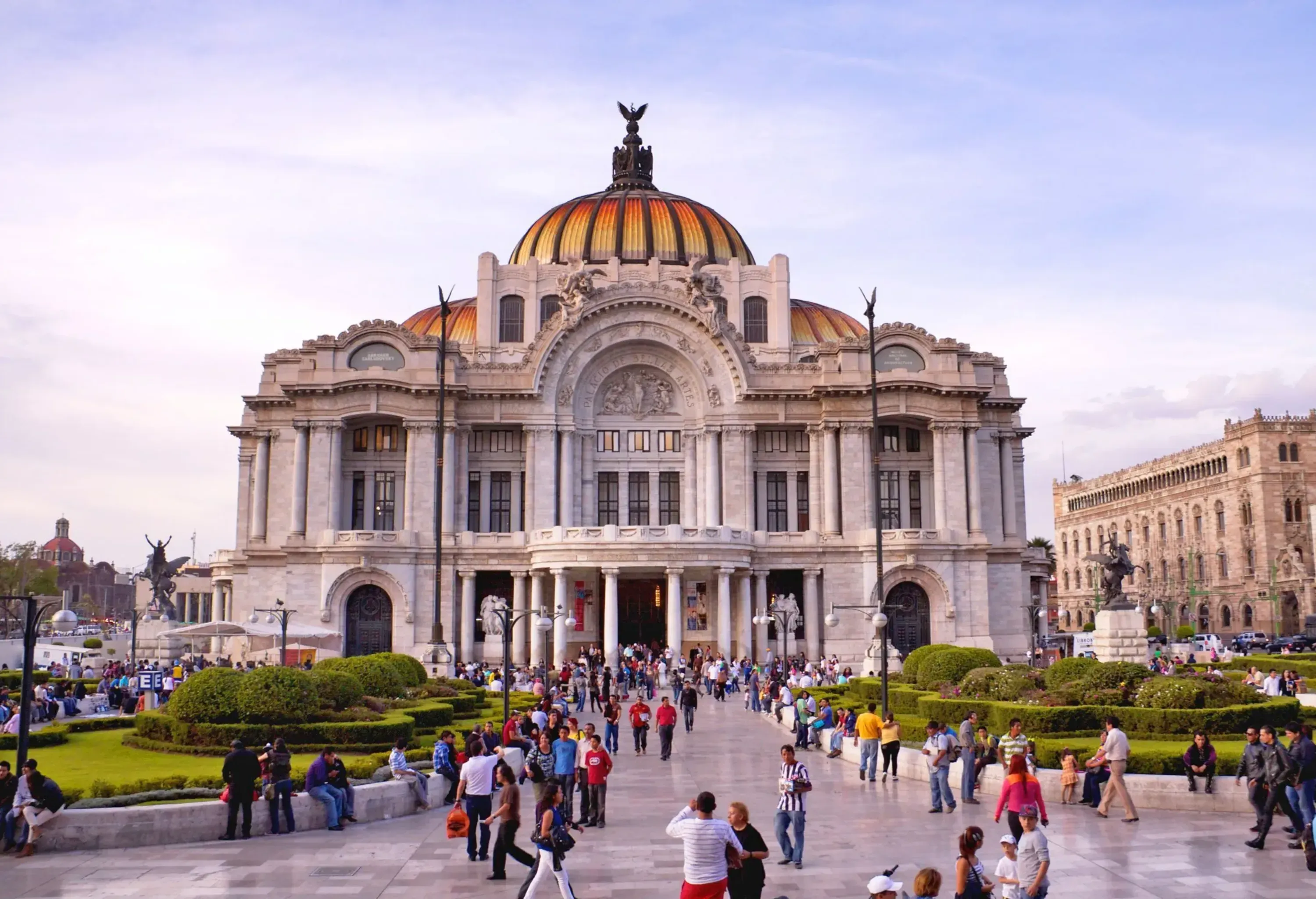 People in front of an impressive neoclassical cultural centre featuring domes, arches, columns and ornate sculptures.