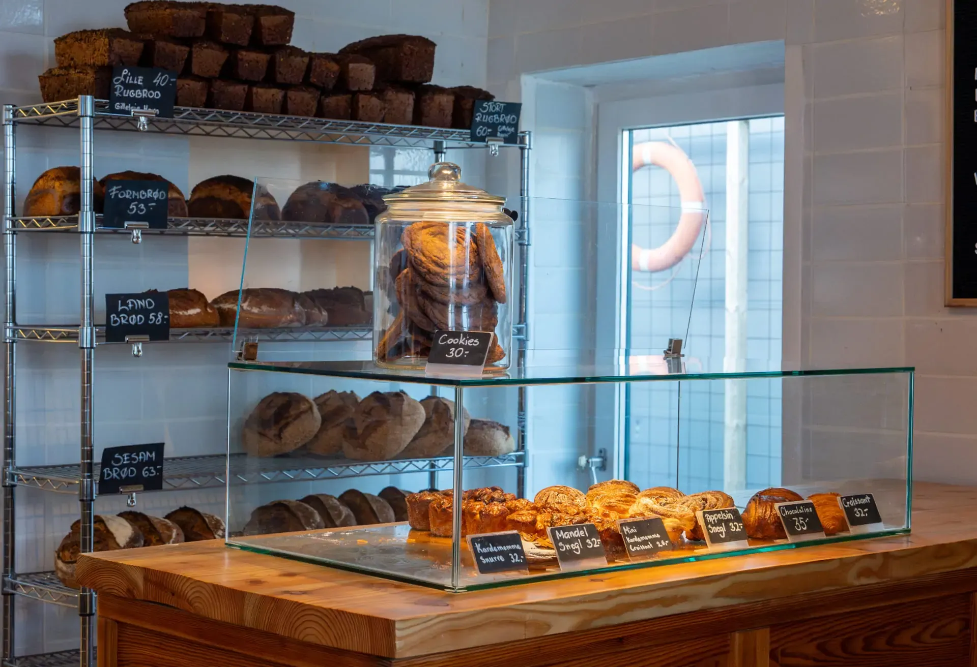 Bakery counter with a glass pastry case and shelves of fresh bread in the background.